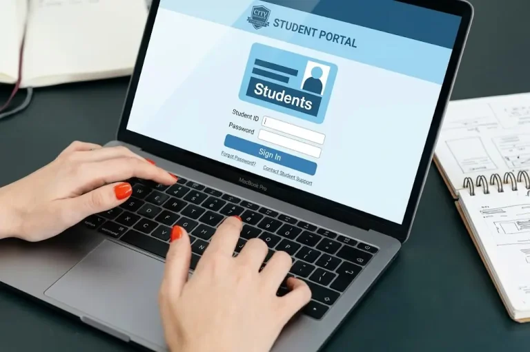 Hands typing on a laptop displaying the Student Portal login screen.   